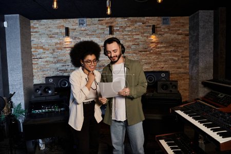 A man and woman stand in a recording studio, immersed in a music band rehearsal session.