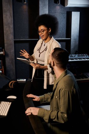 Two individuals from a music band engaging in a discussion within a recording studio setting.