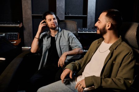 Dos hombres en un estudio de grabación participan en una llamada telefónica durante un ensayo de la banda de música.
