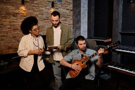 Talentoso grupo de músicos ensayando en un estudio de grabación, con un enfoque en tocar la guitarra y crear música juntos.