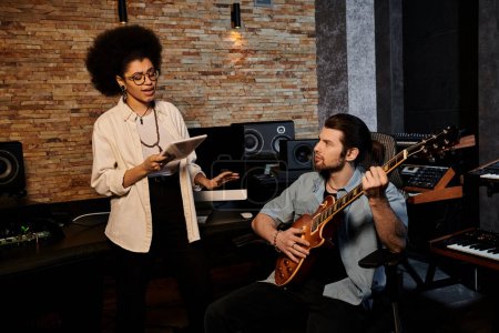Woman and man collaborate in music band rehearsal within recording studio.