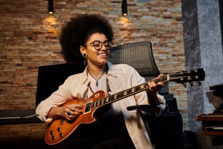 Téléchargez les photos : Femme talentueuse jouant de la guitare acoustique en studio d'enregistrement pendant la répétition du groupe de musique. - en image libre de droit