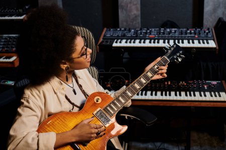 Una mujer talentosa tocando una guitarra con pasión en un estudio de grabación profesional para un ensayo de la banda de música.