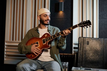 Un músico toca una guitarra en un estudio de grabación durante un ensayo de una banda de música.