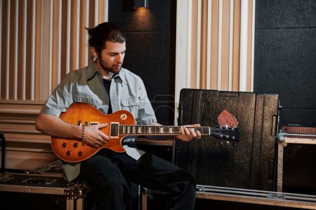 Un hombre toca apasionadamente una guitarra en medio de un equipo de música en un estudio de grabación durante un ensayo de la banda de música.
