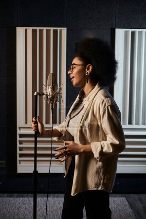 Photo for Talented woman singing passionately into microphone during music band rehearsal in recording studio. - Royalty Free Image
