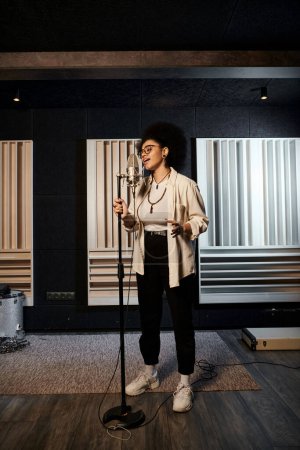 Eine Frau steht selbstbewusst in einem Tonstudio, bereit, bei einer Musikband-Probe ins Mikrofon zu singen.