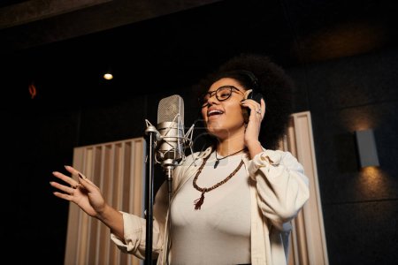 Mujer talentosa canta apasionadamente en el micrófono durante el ensayo de la banda de música en el estudio de grabación.