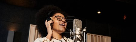 Photo for A female vocalist passionately sings into a microphone in a professional recording studio during a music band rehearsal. - Royalty Free Image