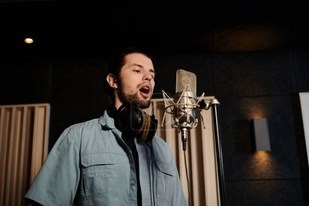 A man passionately sings into a microphone in a recording studio during a music band rehearsal.