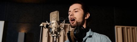Foto de Un hombre talentoso canta apasionadamente en un micrófono, derramando su corazón en un estudio de grabación durante un ensayo de la banda de música. - Imagen libre de derechos