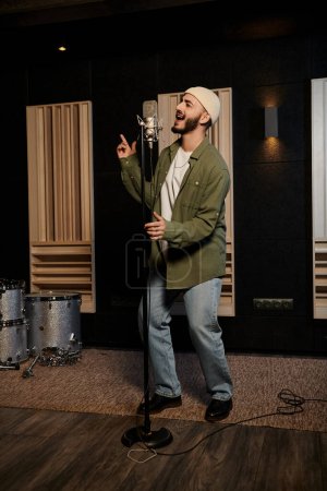 Un homme se tient en confiance dans un studio d'enregistrement, prêt à chanter ou à parler devant un microphone.