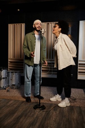 Deux chanteurs se tiennent près du microphone dans un studio d'enregistrement, se préparant pour une répétition du groupe de musique.