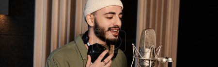 Photo for A man with a beard passionately sings into a microphone during a music band rehearsal in a recording studio. - Royalty Free Image