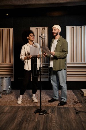 Zwei Personen stehen selbstbewusst vor einem Mikrofon in einem Tonstudio und bereiten sich auf die Probe mit ihrer Musikband vor.