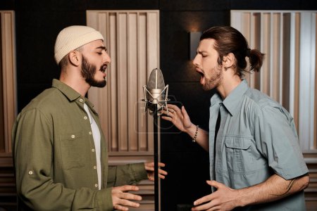 Foto de Dos hombres cantan apasionadamente en un micrófono en un estudio de grabación, perdidos en la música mientras ensayan con su banda. - Imagen libre de derechos