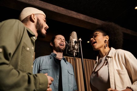 Drei Personen singen während einer Musikband-Probe leidenschaftlich zusammen im Tonstudio.