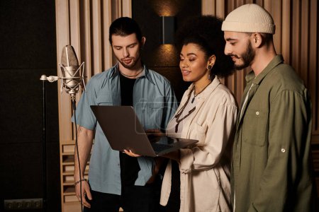 Three individuals collaborating in a recording studio, reviewing music on a laptop screen.