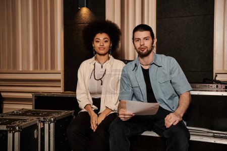 Un hombre y una mujer colaboran en un estudio de grabación, rodeado de instrumentos y equipos musicales.