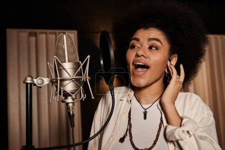 Photo for Talented woman passionately performs vocals into microphone during music band rehearsal in recording studio. - Royalty Free Image