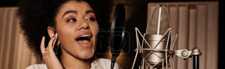 Foto de Una mujer talentosa canta apasionadamente en un micrófono durante un ensayo de la banda de música en un estudio de grabación. - Imagen libre de derechos