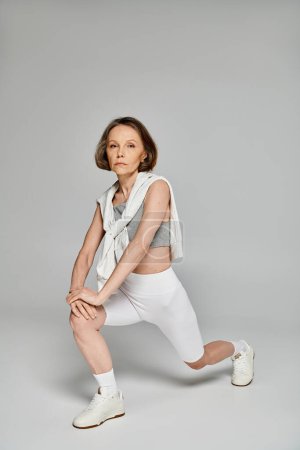 A mature woman squatting gracefully on a white background.