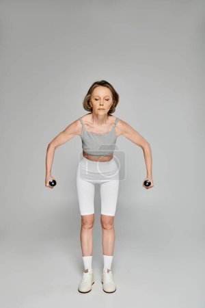 Mujer madura levantando pesas enérgicamente.