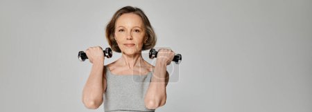 Téléchargez les photos : Fit woman in workout gear holding dumbbells, showing strength and determination. - en image libre de droit