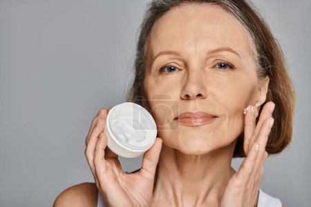 A woman enhancing her beauty by applying cream to her face.