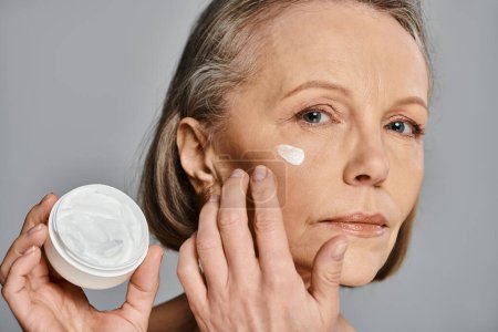 A woman nourishing her skin with cream in a self-care moment.
