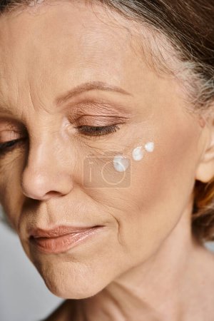 Téléchargez les photos : Une femme avec de la crème sur le visage, incarnant détente et beauté. - en image libre de droit