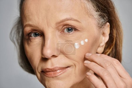 A woman gracefully applies cream to her face.