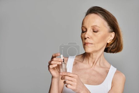 Photo for Woman elegantly holding a serum bottle. - Royalty Free Image