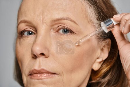 Photo for A woman pampering her skin with serum for ultimate rejuvenation. - Royalty Free Image