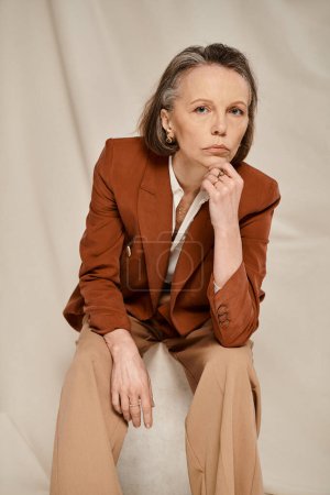 Photo for Stylish woman in brown blazer and tan pants gracefully poses and moves. - Royalty Free Image