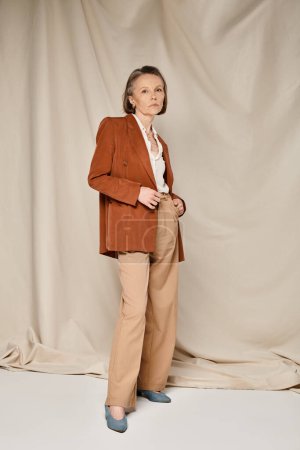 Femme élégante en blazer bronzé et pantalon, respirant la confiance et la sophistication tout en frappant une pose.