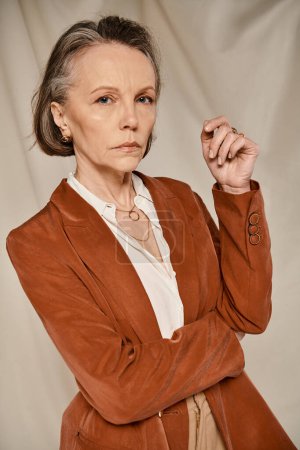 Femme plus âgée en veste bronzée frappant une pose gracieuse pour une photo.