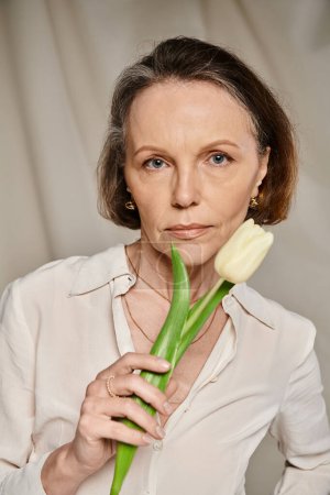 Téléchargez les photos : Femme en chemise blanche tient gracieusement la tulipe. - en image libre de droit