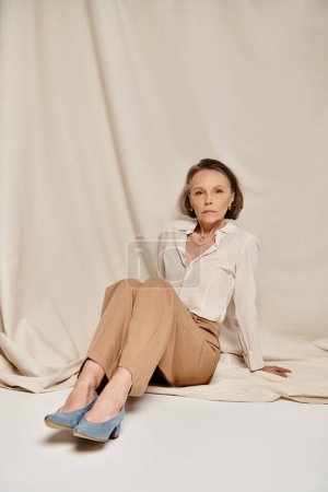 Photo for A mature woman in a tan shirt relaxes gracefully on a bed. - Royalty Free Image