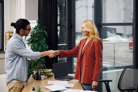 A man and woman shake hands in an office, sealing a business partnership.
