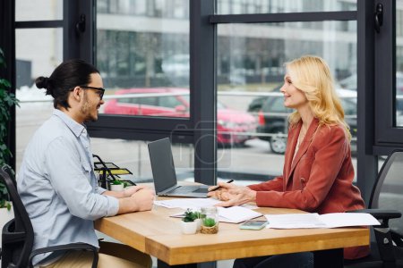 Photo for Man and woman engaging in discussion at a desk in an office setting. - Royalty Free Image