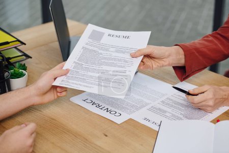Un hombre le entrega un currículum a una mujer durante una entrevista de trabajo.