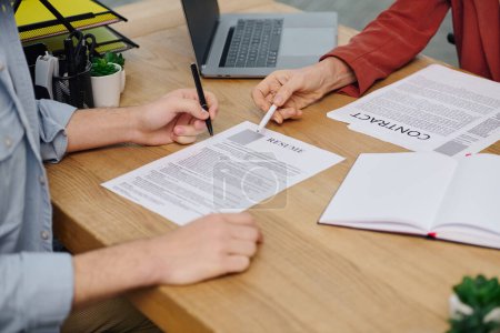 Deux personnes à une table, signant un document lors d'un entretien d'embauche.
