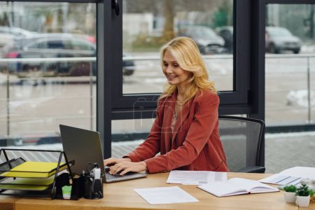 Foto de Una mujer se sienta en un escritorio con una laptop, enfocada en su trabajo. - Imagen libre de derechos