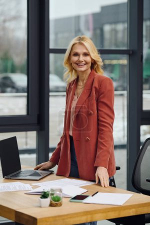 A woman focuses, standing at a desk with laptop.