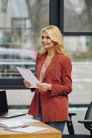 Una mujer está parada en un escritorio, sosteniendo un papel.