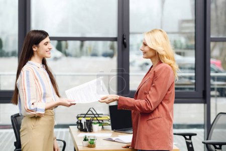 Two women shaking hands in an office during a job interview.