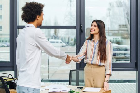 Photo for A man and woman shaking hands in an office setting. - Royalty Free Image