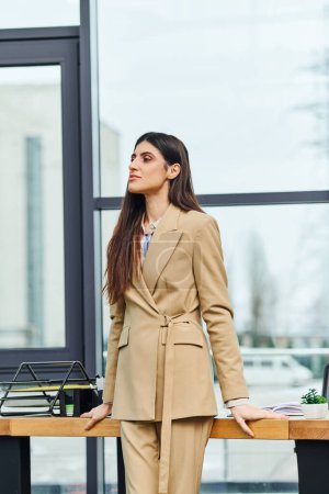 Téléchargez les photos : Une femme en costume bronzé se tient en confiance devant un bureau. - en image libre de droit