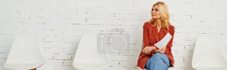 Photo for A woman sits elegantly on a white chair in a waiting room. - Royalty Free Image